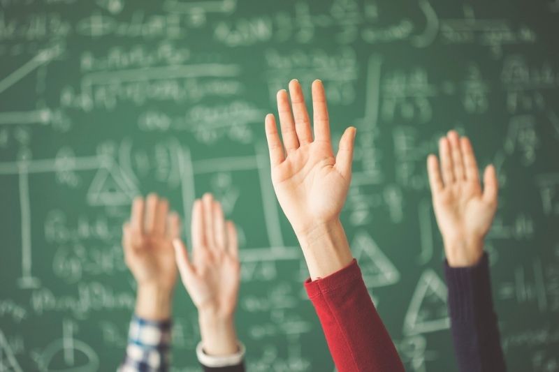 Hands raised in front of chalkboard.